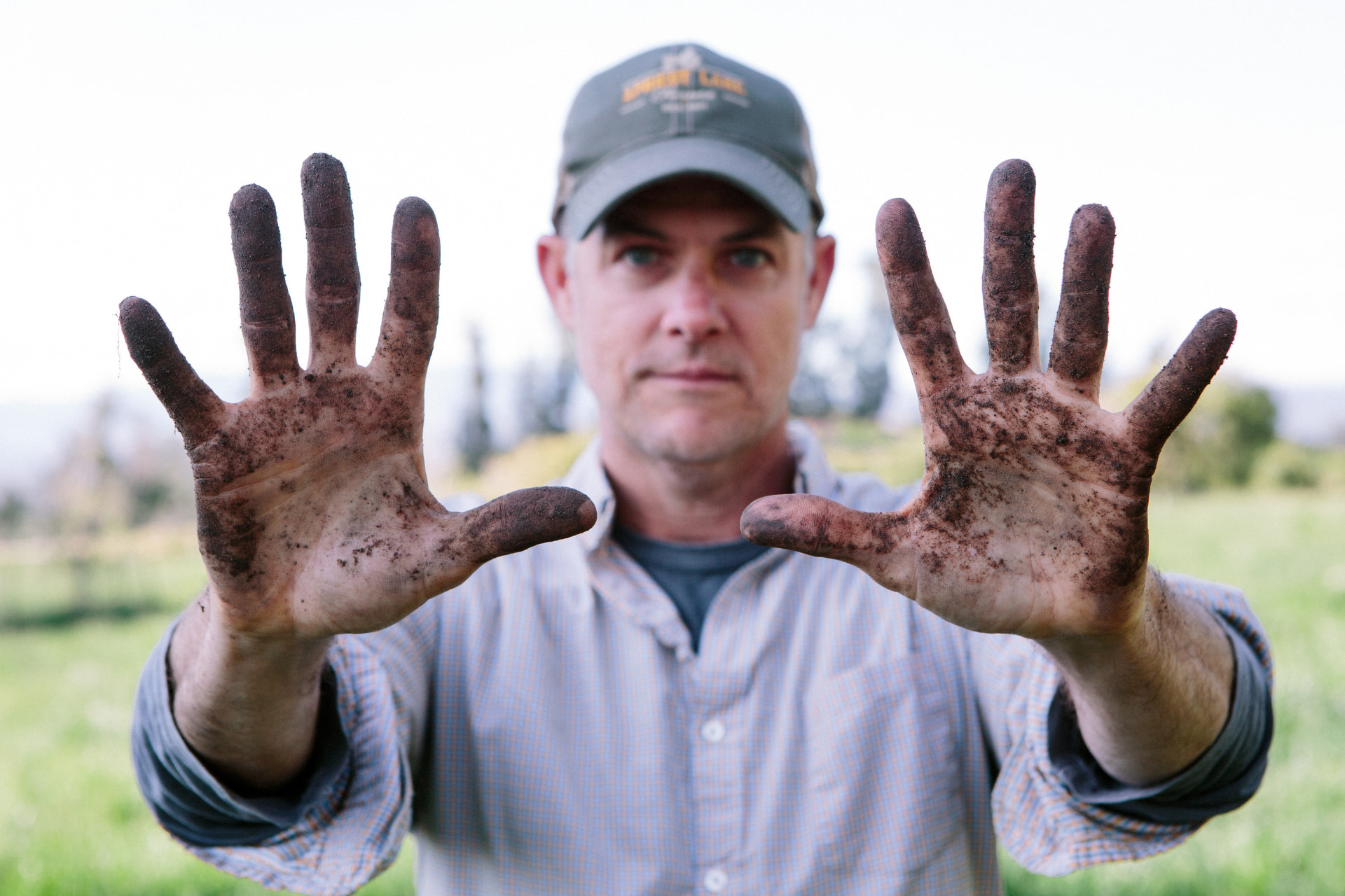 John Chester holding up his soil-covered hands on the farm